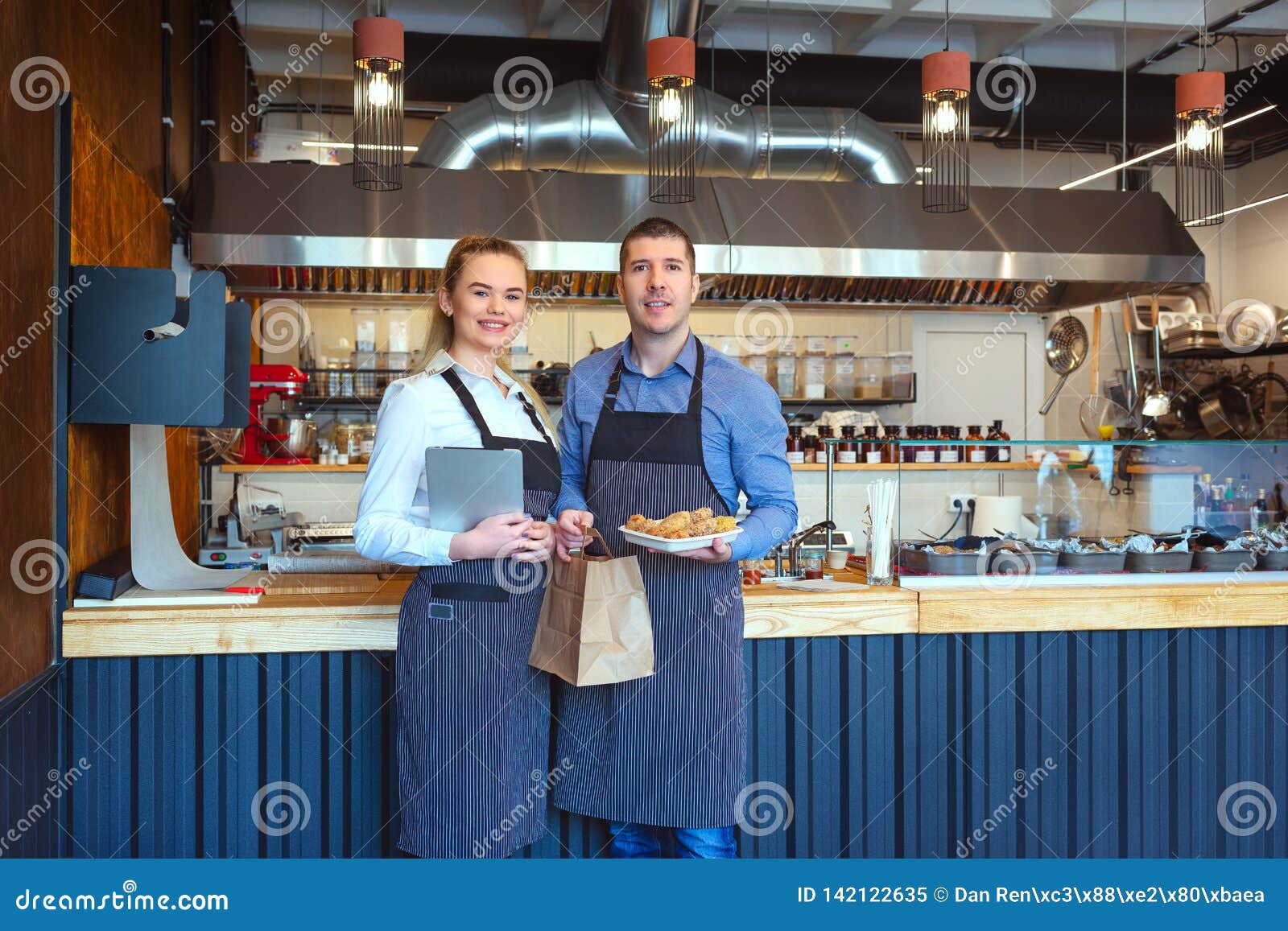 smiling young man and woman using tablet at small eatery restaurant